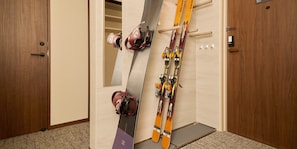 A room with a wooden door, a wall-mounted ski rack, and a carpeted floor. - Rakuten STAY Niseko (Niseko)