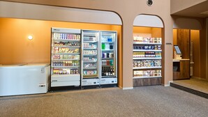 Et hotel lobby med en selvbetjeningsområde for drikkevarer, en kassebod samt et siddeområde.