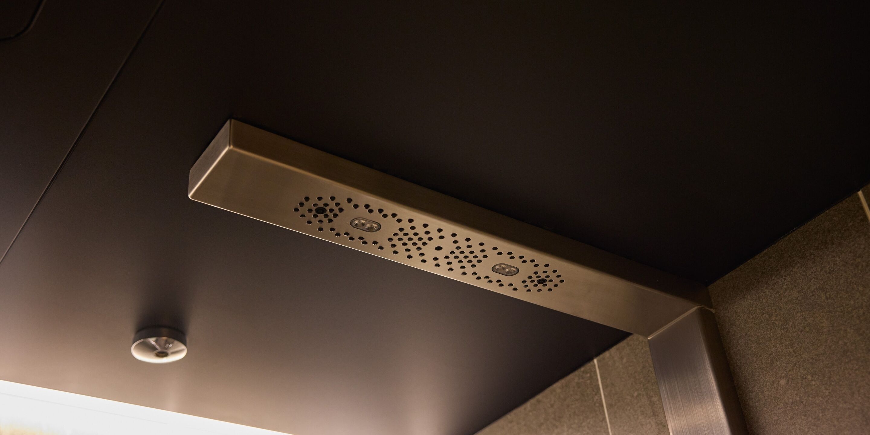 Uma casa de banho moderna com um chuveiro metálico elegante e uma luminária suspensa no teto.