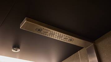 Uma casa de banho moderna com um chuveiro metálico elegante e uma luminária suspensa no teto.