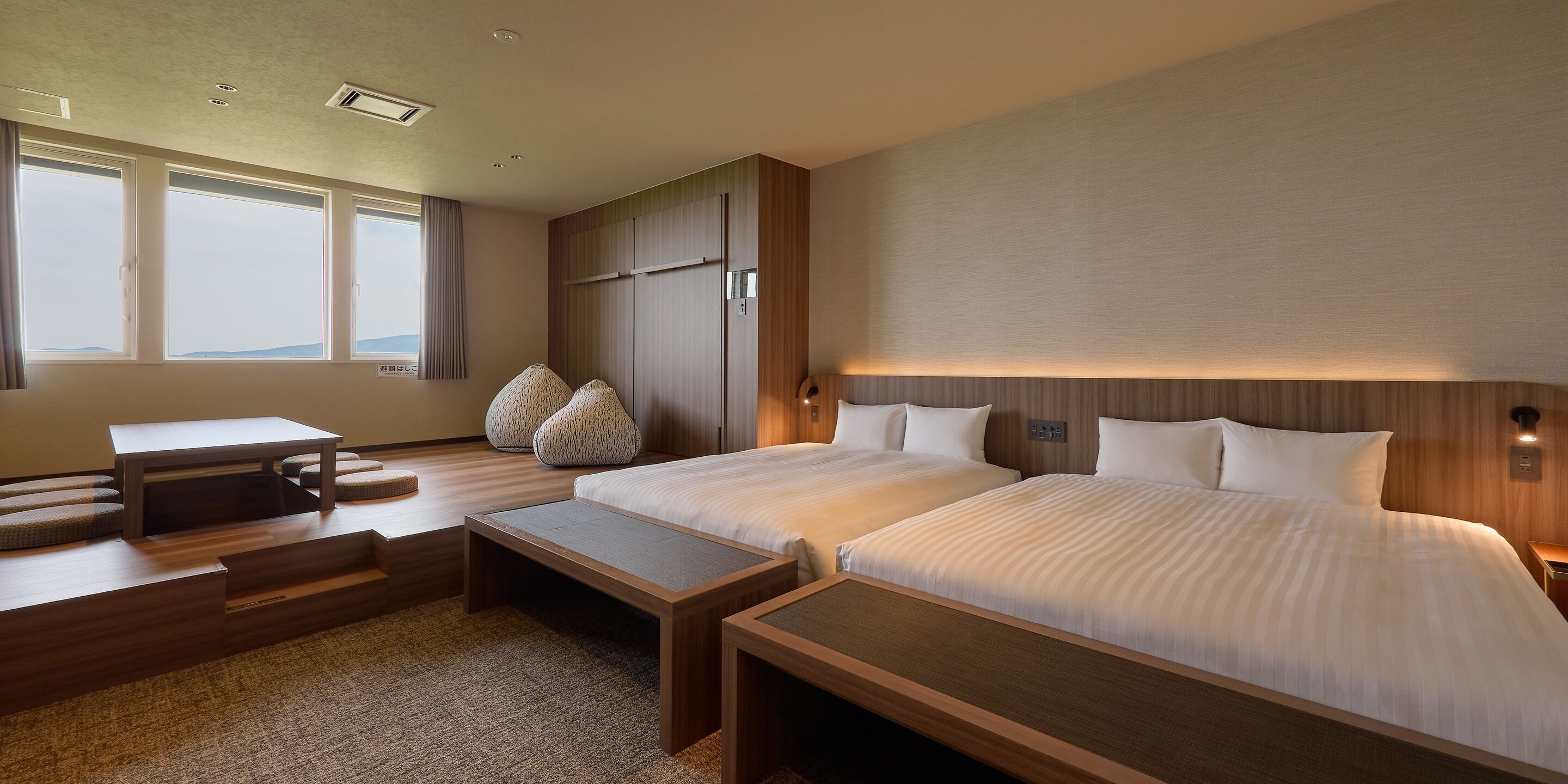 A hotel room with two beds, a desk, and a seating area.
