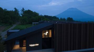 Un bâtiment moderne doté d’un toit en pente, d’une entrée bien visible et d’une enseigne indiquant « Rakuten STAY ».