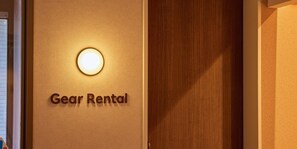 A wall with a sign that reads 'Gear Rental' and a circular light fixture above it.
