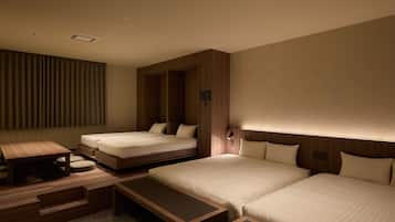 Habitación de hotel con dos camas, una mesita y un banco.