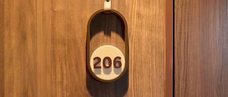 A wooden door with a brass doorbell and a white circular plaque with the number '206'.