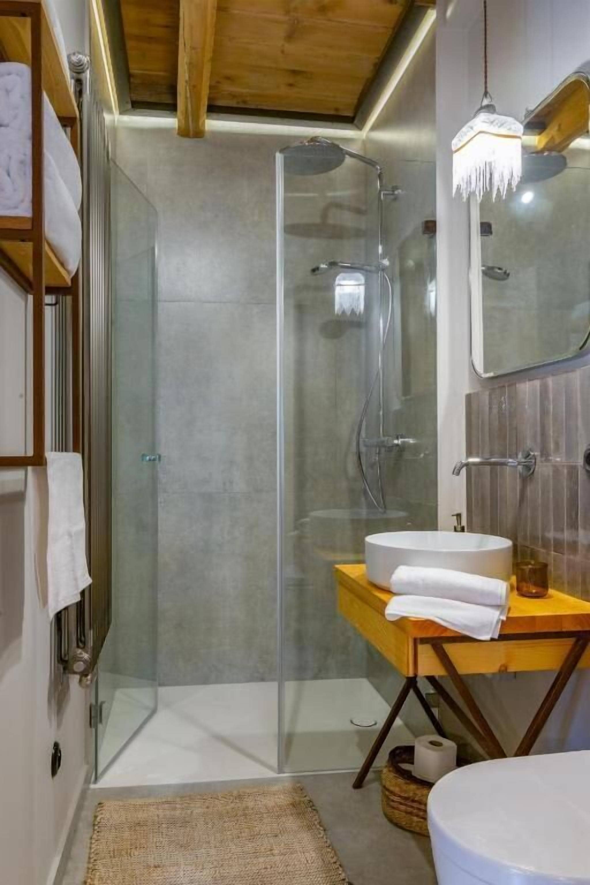 Un bagno moderno con doccia vetro, un mobile bagno in legno con lavello e uno specchio.