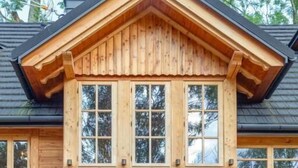 Ein zweistöckiges Holzhaus mit Satteldach und großen Fenstern.