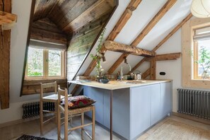 A kitchen with a wooden ceiling, a central island, a chair, and a radiator.