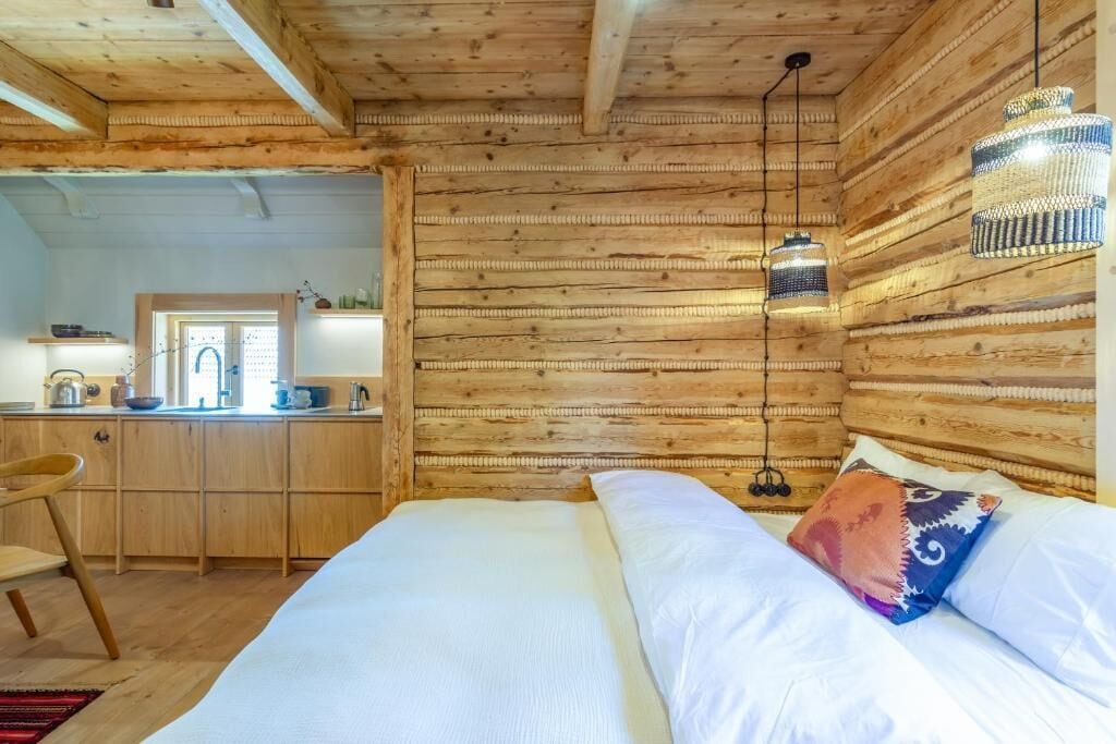 A wooden cabin interior with a bed, a desk, and a hanging light fixture.