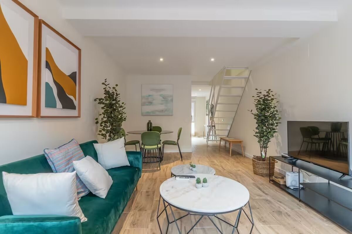 A modern living room with a green sofa, a round coffee table, and a flat-screen TV.