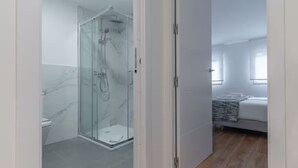 A modern bathroom with a glass-enclosed shower, a toilet, and a white sink. - Edmond Vibes Plaza de Castilla (Madrid)