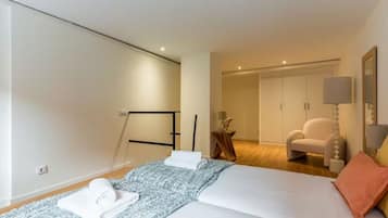 A hotel room with a bed, a chair, a wardrobe, and a lamp.