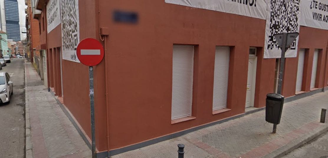 Un edificio con fachada roja, un cartel de ‘prohibido el paso’ y contraventanas cerradas.