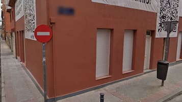 Un edificio con fachada roja, un cartel de ‘prohibido el paso’ y contraventanas cerradas.