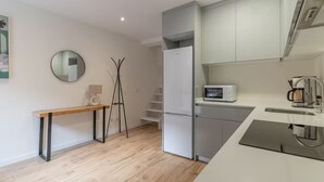 A modern kitchen with a built-in microwave, a coffee maker, and a refrigerator. - Edmond Vibes Plaza de Castilla (Madrid)