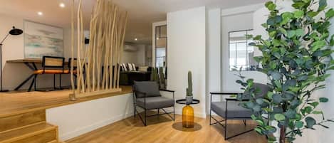Un espacio de sala moderno con escaleras, asientos y una planta grande.