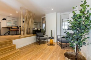 Un espacio de sala moderno con escaleras, asientos y una planta grande.