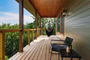 A wooden deck with a hammock, a table with a vase, and a chair. - Indoor Pool + Game Room + BBQ | Mins to Dollywood | Spurling Escape (Sevierville)