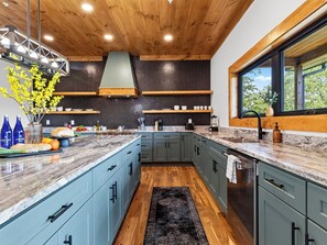 Una cocina moderna con armarios azul claro, encimera de mármol y alfombra negra.