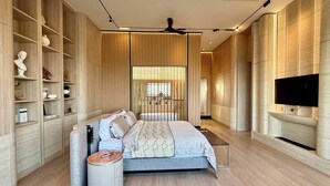 Um quarto moderno com uma cama, mesas de cabeceira, uma televisão e estantes embutidas.