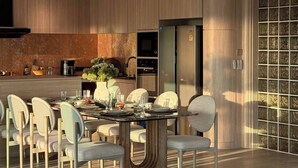 Uma cozinha moderna com eletrodomésticos embutidos, uma sala de jantar com mesa de vidro e uma janela grande com painéis de vidro decorativos.