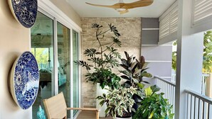 Uma varanda com mesa, cadeiras, pratos decorativos e plantas em vasos.