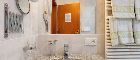 A bathroom with a sink, mirror, towel rack, and a door leading to another room.