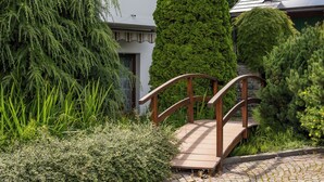 A wooden bridge over a cobblestone path leading to a building with a white facade and a stone wall. - B&B Villa Pattis (Vipiteno)