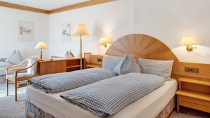 A hotel room with a bed, two bedside tables, a desk, a chair, and two wall-mounted lamps. - B&B Villa Pattis (Vipiteno)