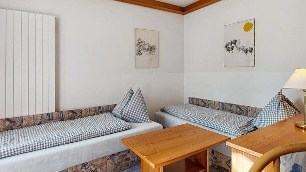 A room with two sofas, a wooden table, and two wall-mounted artworks. - B&B Villa Pattis (Vipiteno)