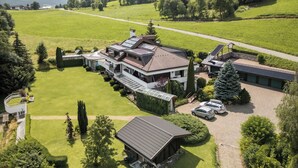 A large, modern house with multiple levels, a spacious lawn, and a driveway with parked cars. - B&B Villa Pattis (Vipiteno)