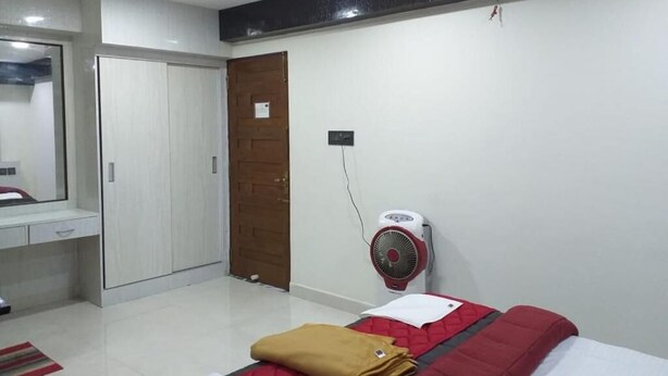 A bedroom with a bed, a wardrobe, a mirror, and a wall-mounted fan. - Grand Meridian By Go2 Hotels and Resorts (Ambur)
