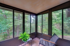A room with large windows, a chair, and a table with a plant. - Fire Pit & Lake Access! Crossville Group Escape (Crossville)