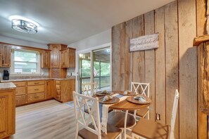 A kitchen with wooden cabinets, a dining table with chairs, and a window. - Fire Pit & Lake Access! Crossville Group Escape (Crossville)