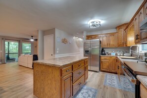 A modern kitchen with wooden cabinets, a central island, and a stainless steel refrigerator. - Fire Pit & Lake Access! Crossville Group Escape (Crossville)