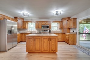 A kitchen with wooden cabinets, a stainless steel refrigerator, and a large island. - Fire Pit & Lake Access! Crossville Group Escape (Crossville)