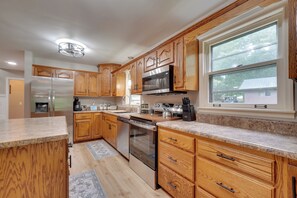 A modern kitchen with wooden cabinets, stainless steel appliances, and a large window. - Fire Pit & Lake Access! Crossville Group Escape (Crossville)