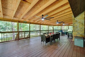 Un espace extérieur abrité, doté d’une terrasse en bois, d’une table dressée pour les repas et d’un mur en pierre.