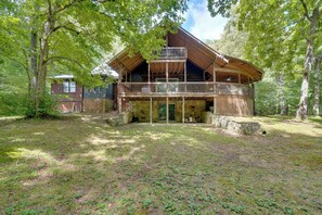 Une cabane en rondins à deux étages, dotée d’un balcon et d’une fondation en pierre.