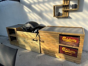 Ein Holzkohlegrill aus Holz mit schwarmem Deckel, auf einer Betonplatte platziert.