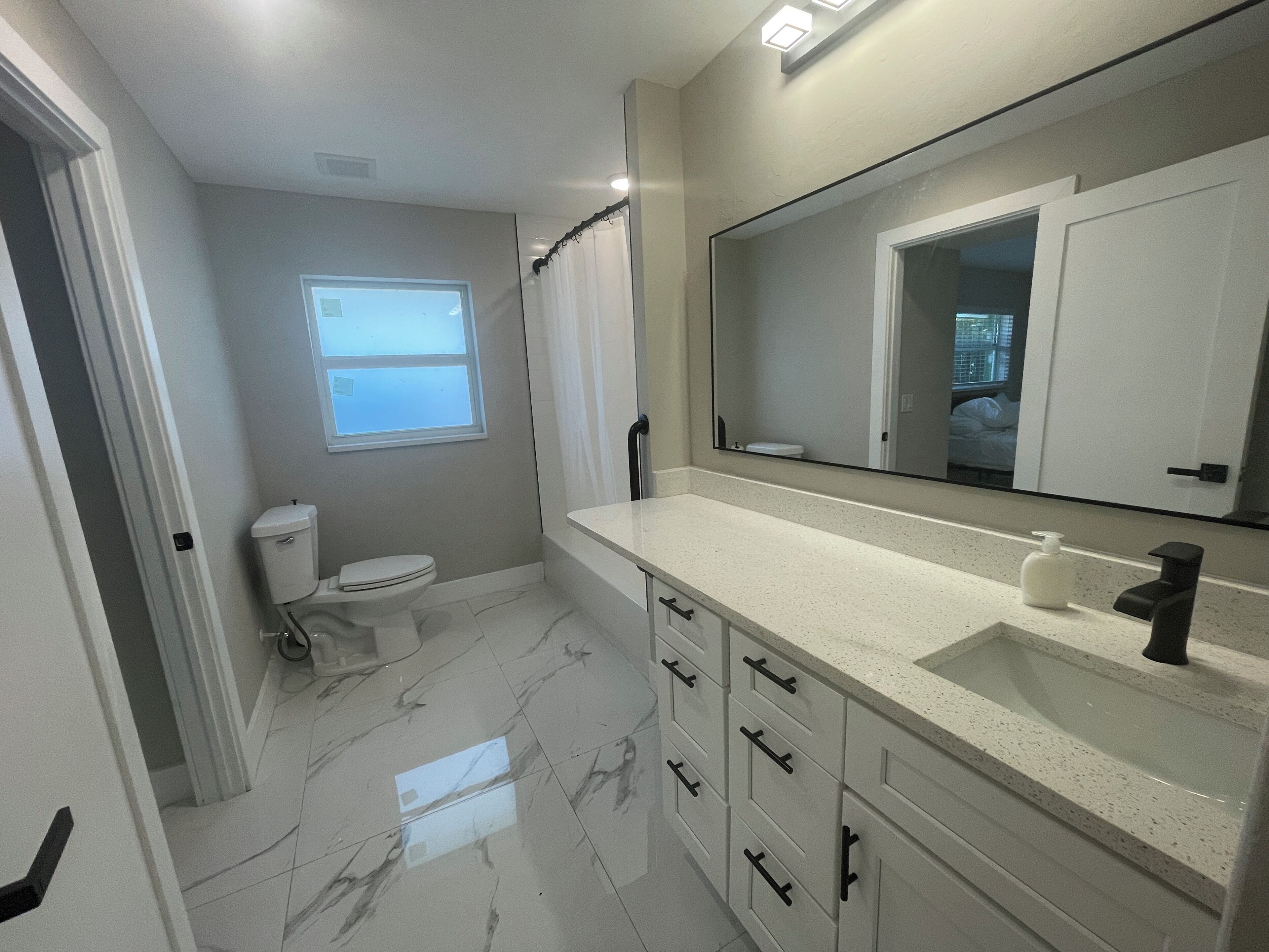Une salle de bain équip ée de toilettes, d’un lavabo, d’un miroir et d’un rideau de douche.