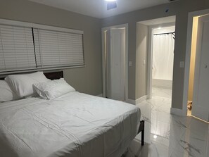 A bedroom with a bed, white curtains, and a door leading to a bathroom. - Waterfront getaway, relaxation done right here (Fort Myers)