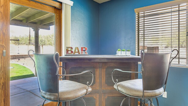Een bar met twee stoelen, een houten plafond en uitzicht op het omliggende landschap.