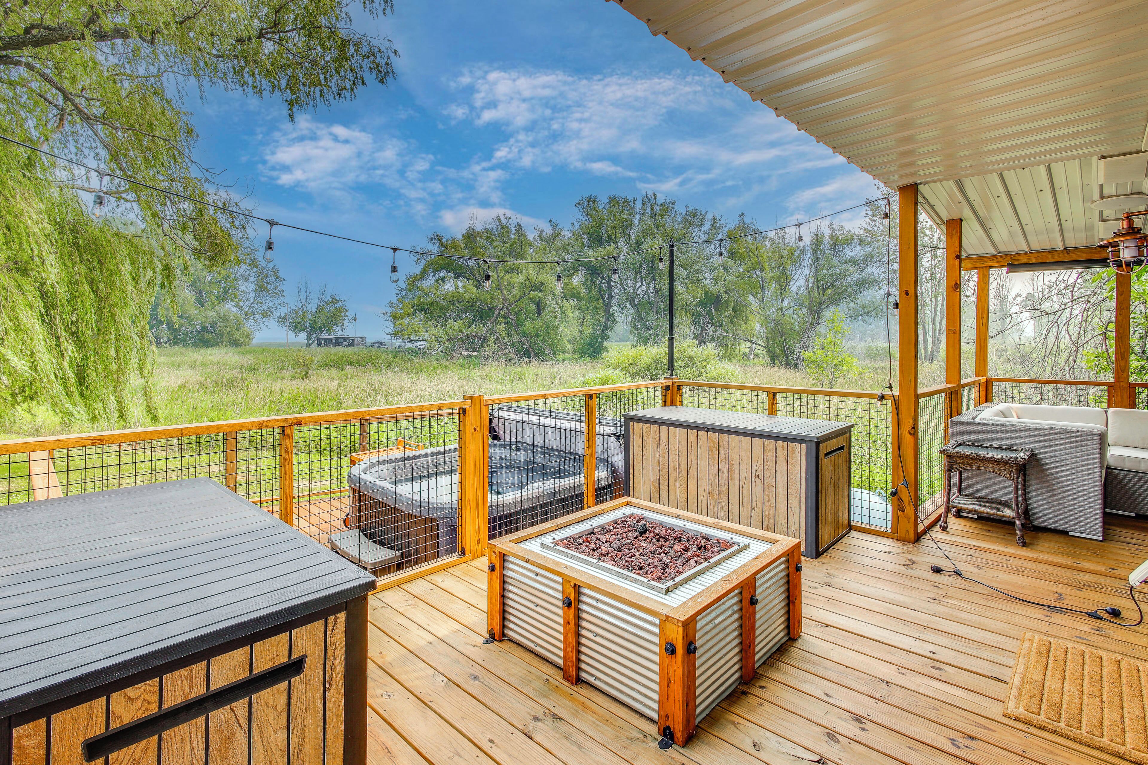 Eine Holzterrasse mit Gartenmöbeln, einem Grill und Blick auf eine natürliche Landschaft.
