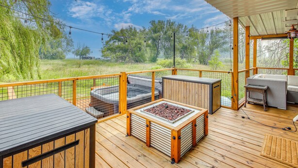 A wooden deck with outdoor furniture, a grill, and a view of a natural landscape. - Bayfront Home! Dock, Deck, Hot Tub, & Fire Pit (Oconto)