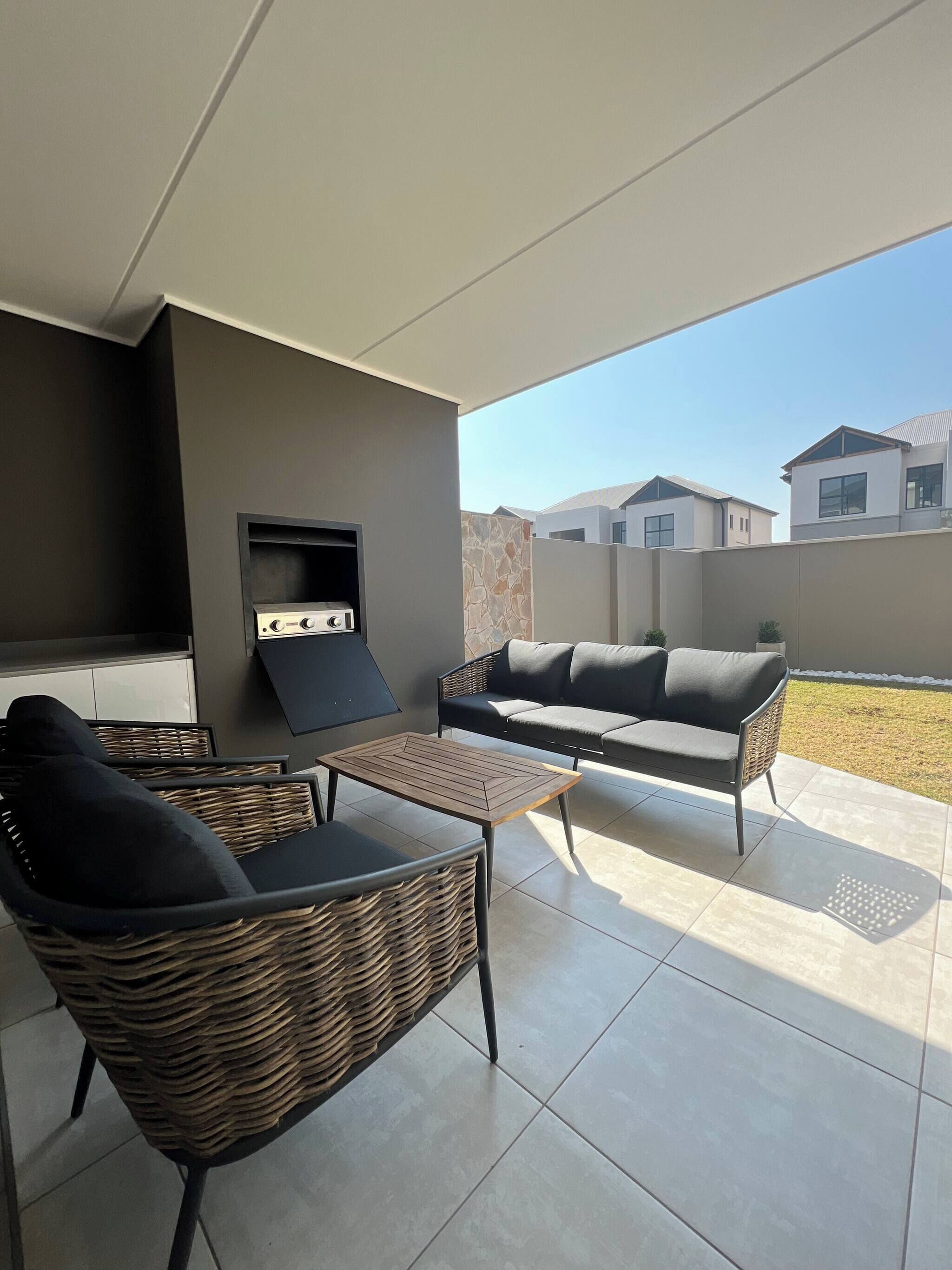 A patio area with wicker furniture, a flat-screen TV, and a grill.