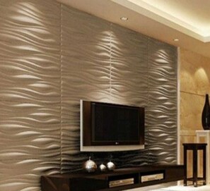 Una sala de estar moderna con una pared texturizada, un televisor de pantalla plana sobre un soporte de madera y una mesita con objetos decorativos.