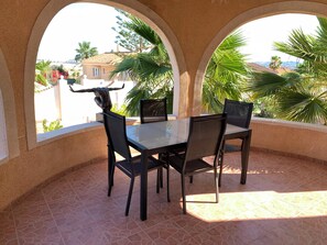 Eine Terrasse mit Tisch und Stühlen, Blick auf eine Wohngegend und eine Statue.