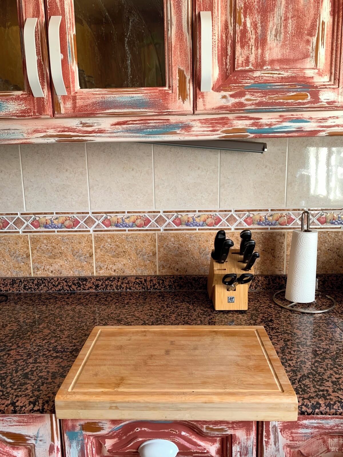 Una cucina con un tagliere di legno, un portacoltelli e un porta asciugamani di carta.