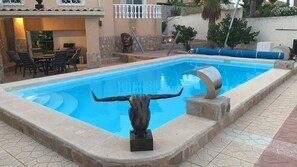 A swimming pool with a bull's head sculpture in the center, surrounded by a tiled patio area. - Casa Czuberny – Holiday Retreat (VC)